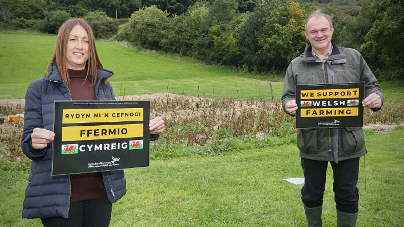 Welsh Lib Dem Leader Jane Dodds and UK Leader Ed Davey holding signs saying "Back Welsh Farming"