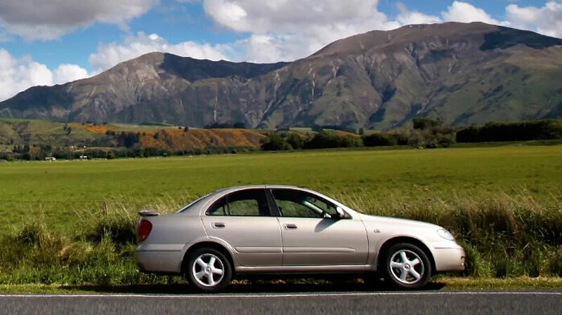A car in front of a mountain on a rural road
