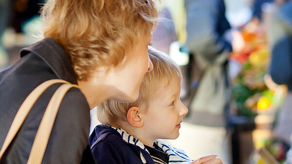 A mother and son picking which apple to buy.